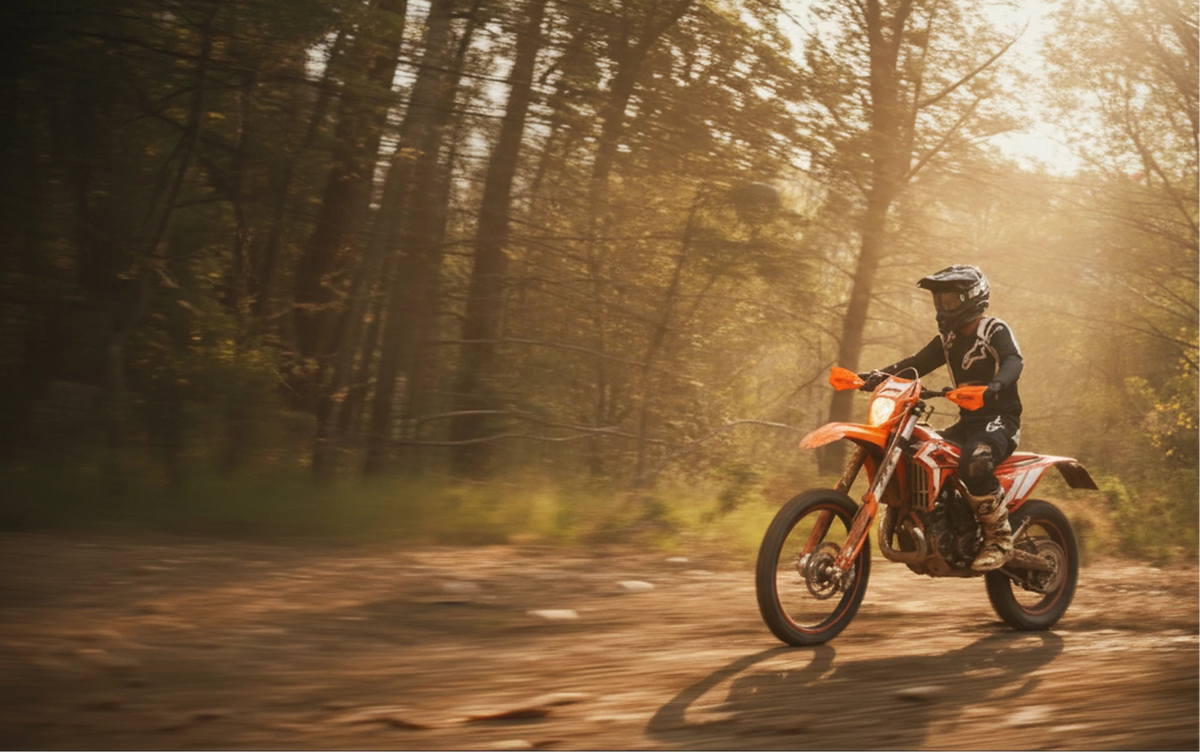 Person riding a beta dirt bike on a forest trail with warm sunlight filtering through the trees. He has R16V suspensions.
